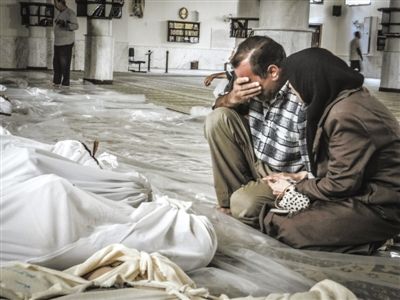 21日，大马士革郊区，一对夫妻在自己遇难的孩子遗体旁哭泣。