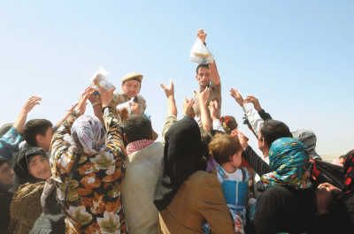 8月24日，在伊拉克和叙利亚边境萨赫拉临时难民接待中心，叙利亚难民领取水和食物。来源：新华网