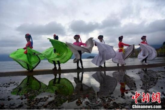 一群女子穿着摩梭服饰在泸沽湖畔留下倩影。