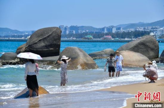 6月8日，海南三亚，游客在天涯海角游览区沙滩游玩。当日，恰逢世界海洋日，海南省三亚市天涯海角游览区迎来大批游客。蔚蓝海面游船穿梭，沙滩上游客尽情玩耍、拍摄留念，尽情感受海洋生态的独特魅力。中新社记者