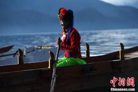 穿着摩梭服饰的女子乘坐小木船。