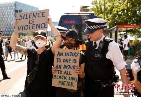 　　5月31日，英国伦敦，当地警察站在手持标语的抗议者身前。