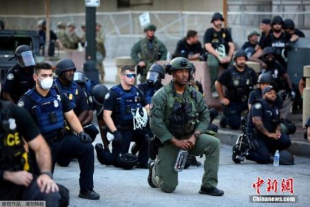 　　当地时间6月1日，美国乔治亚州亚特兰大市中心，警察和参加游行示威活动的民众一起跪地抗议针对美国非裔男子暴力执法的行为。